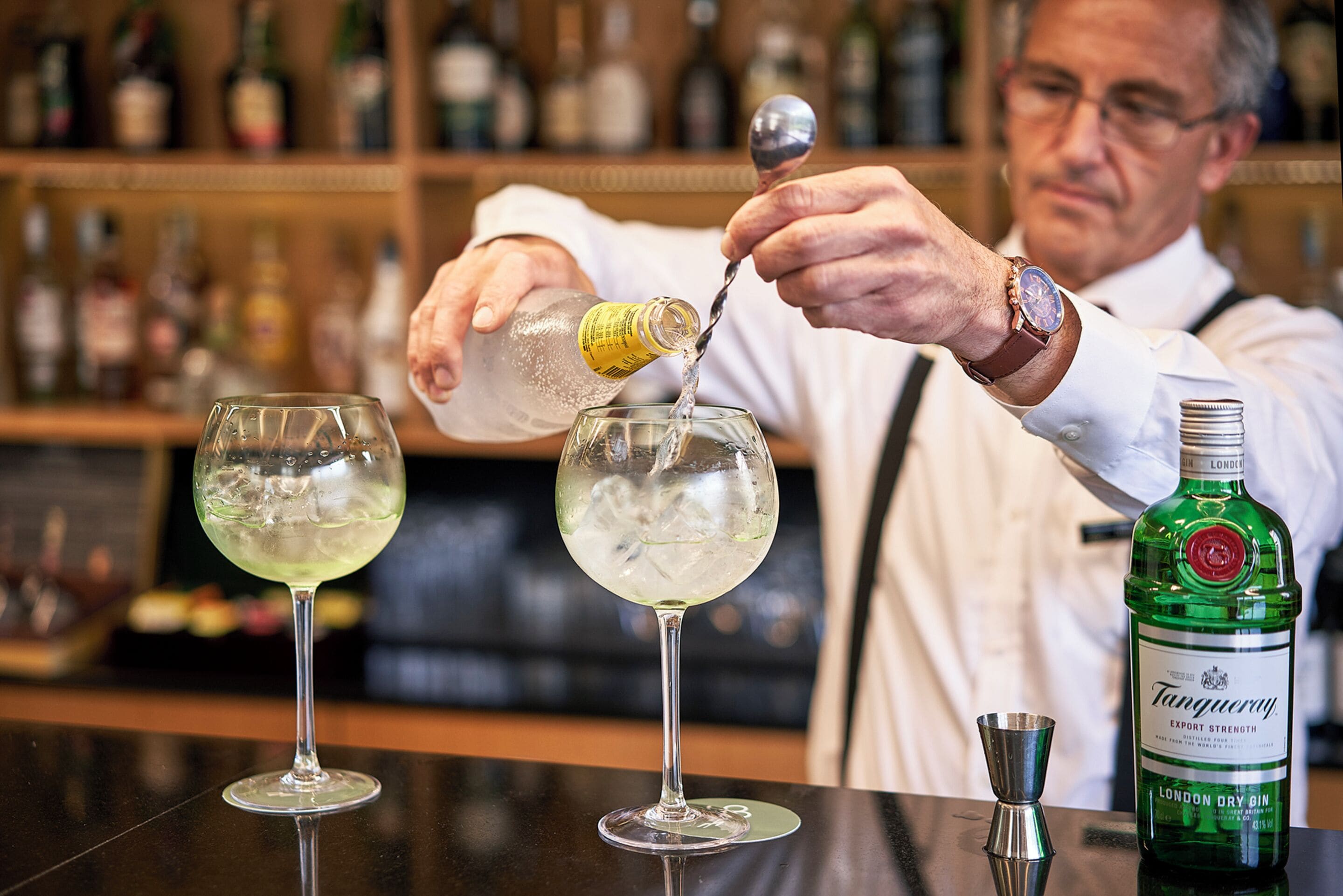 A bartender pouring a drink into a glass.