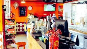 A brightly lit snack bar with a counter, a television, and various food items. - Castillo Beach Club Apartments (Antigua)
