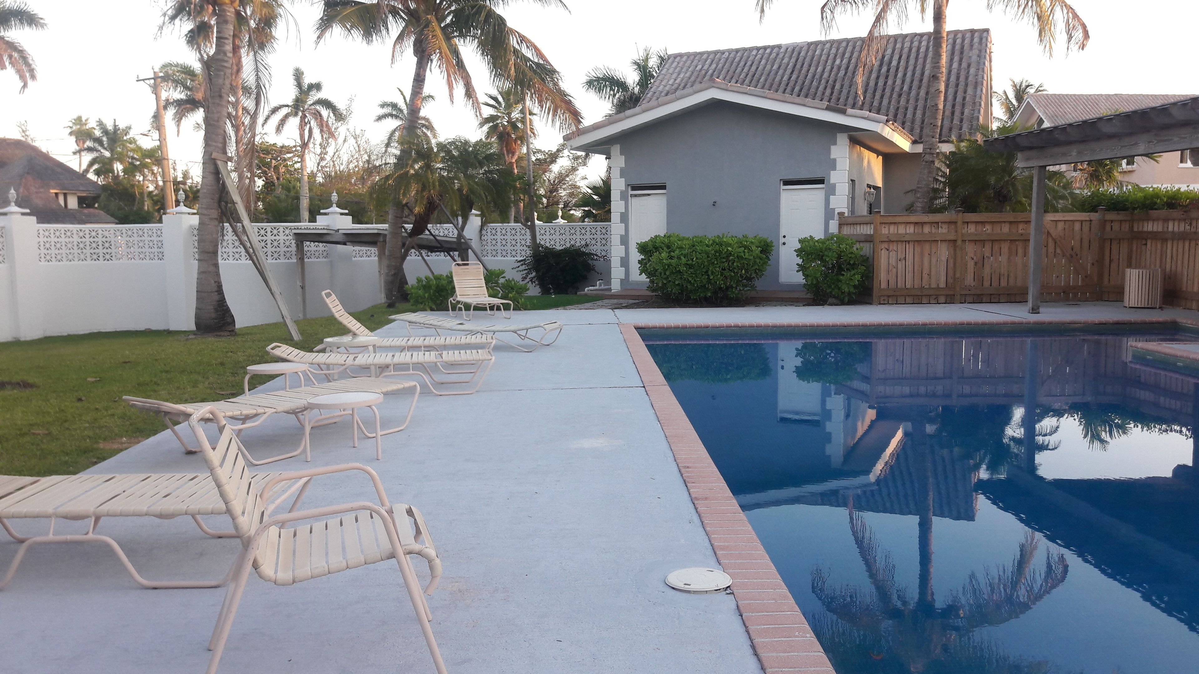 Una piscina con sillas de descanso y una casa al fondo.