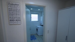 Un cuarto de lavandería con lavadora, un tendedero y una ventana.