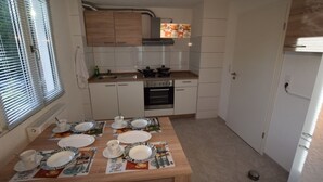 Una cocina compacta con armarios blancos, una encimera de madera y una mesa de comedor preparada para cuatro comensales.