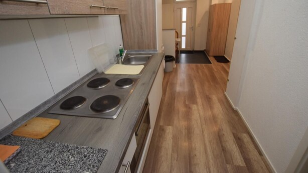 Une cuisine équipée d’une cuisinière, d’un évier et de meubles de rangement en bois.