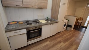 Une cuisine compacte équipée d’une cuisinière, d’un four, d’un évier et d’un lave-linge.