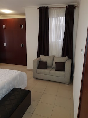 A bedroom with a bed, a sofa, and a wardrobe.