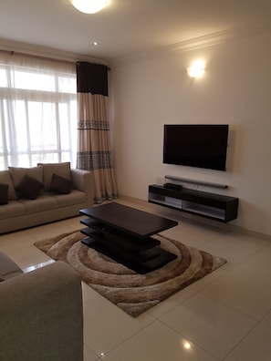 A modern living room with a sofa, a coffee table, a TV, and a patterned rug.