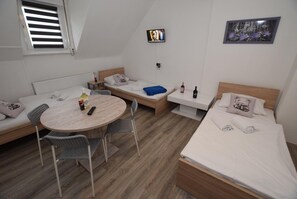 Una habitación compacta con una cama, un sofá, una mesita y un televisor.