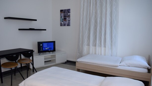 Une chambre d’hôtel avec un lit, un bureau équipé d’un ordinateur et une chaise.
