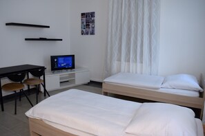 Quarto de hotel com uma cama, uma escrivaninha com um computador e uma cadeira.