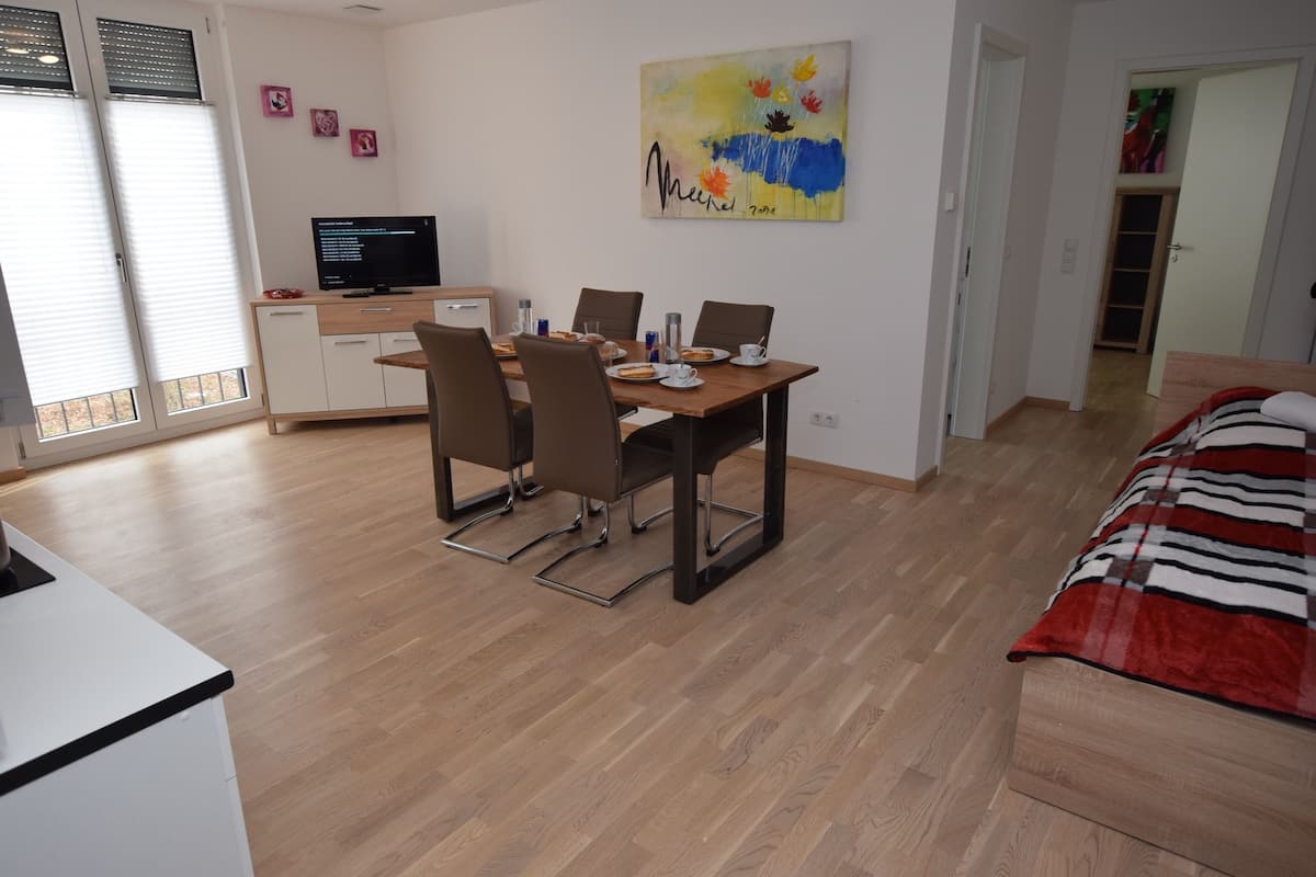 Un coin repas avec une table en bois, des chaises et un téléviseur posé sur un meuble.