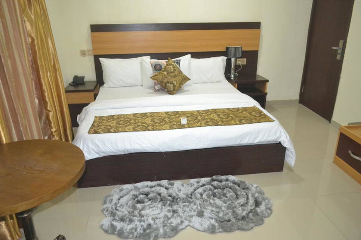 A hotel room with a bed, bedside tables, a round table, and a decorative rug.
