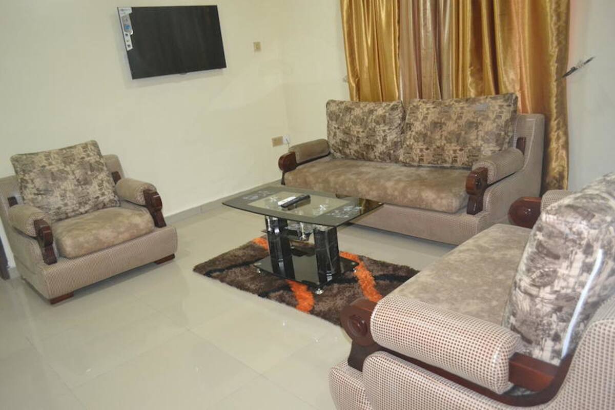 A living room with two armchairs, a sofa, and a glass coffee table.