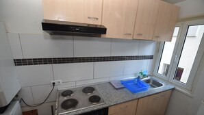 A kitchen with a stove, sink, and wooden cabinets. - AB Apartment 15 (Stuttgart)