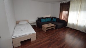Une pièce comprenant un lit, un canapé, une table basse et une fenêtre avec des rideaux.