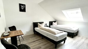 A modern, compact room with two single beds, a small table, and a chair. - Landhotel Laarmann (Lennestadt)