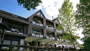 A multi-story building with balconies, potted plants, and outdoor seating. - Landhotel Laarmann (Lennestadt)