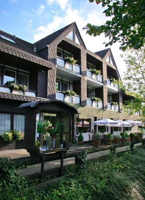 A multi-story hotel with balconies, outdoor seating, and a small shop. - Landhotel Laarmann (Lennestadt)
