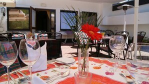 An outdoor dining area with tables set for two, featuring clear glassware and a red flower centerpiece. - Landhotel Laarmann (Lennestadt)