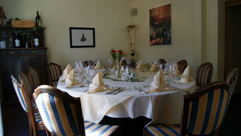 A dining room with a round table set for a meal, surrounded by striped chairs.