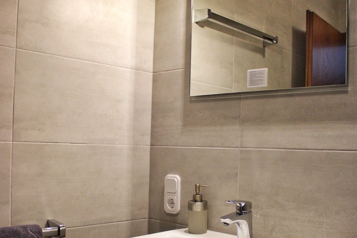 A bathroom with a white sink, a mirror, and a towel rack.