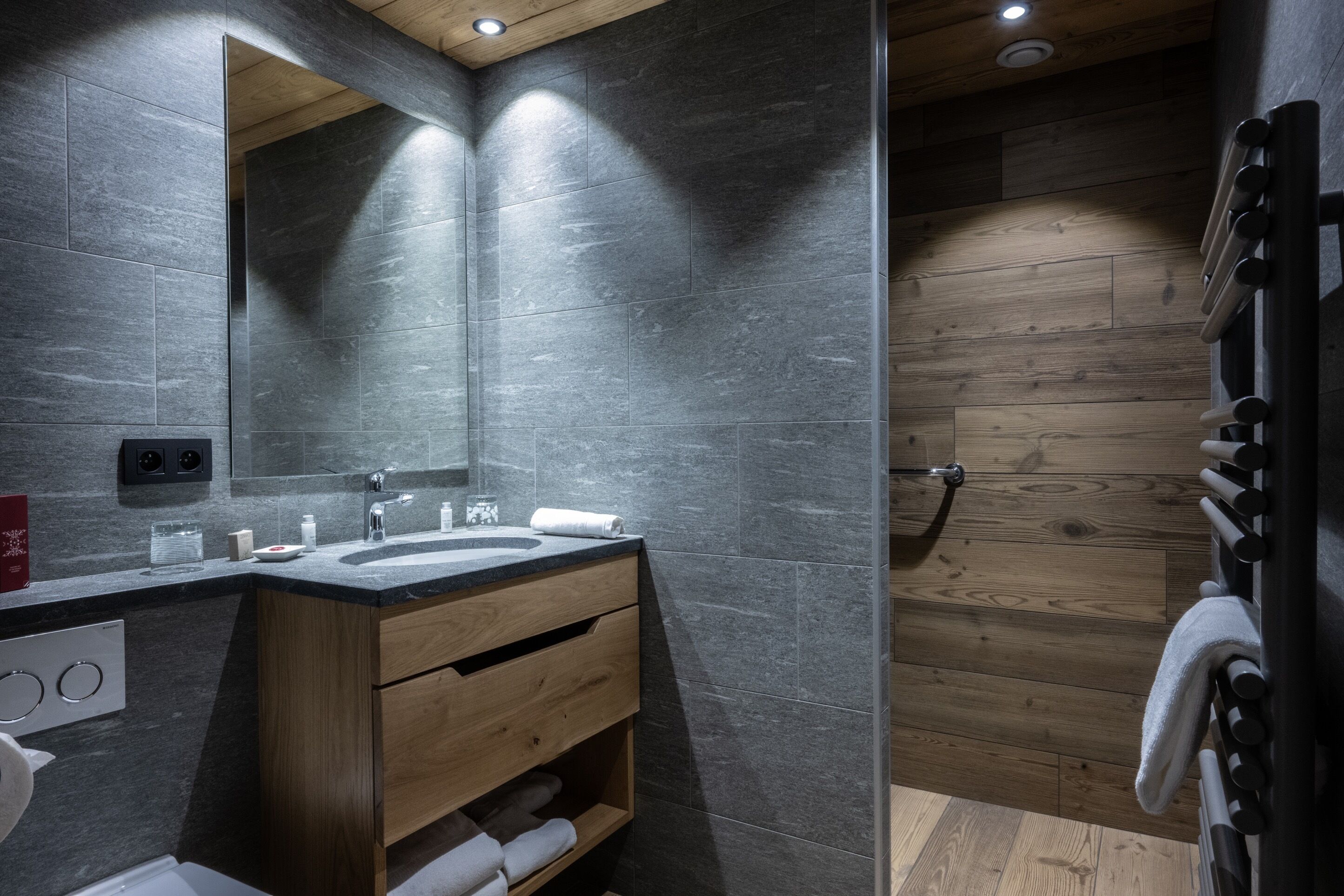 A modern bathroom with a wooden vanity, a large mirror, and a shower area.