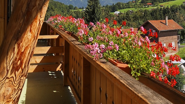 A wooden balcony with a view of snow-capped mountains and a green valley. - Le Chamois d'Or (Cordon)