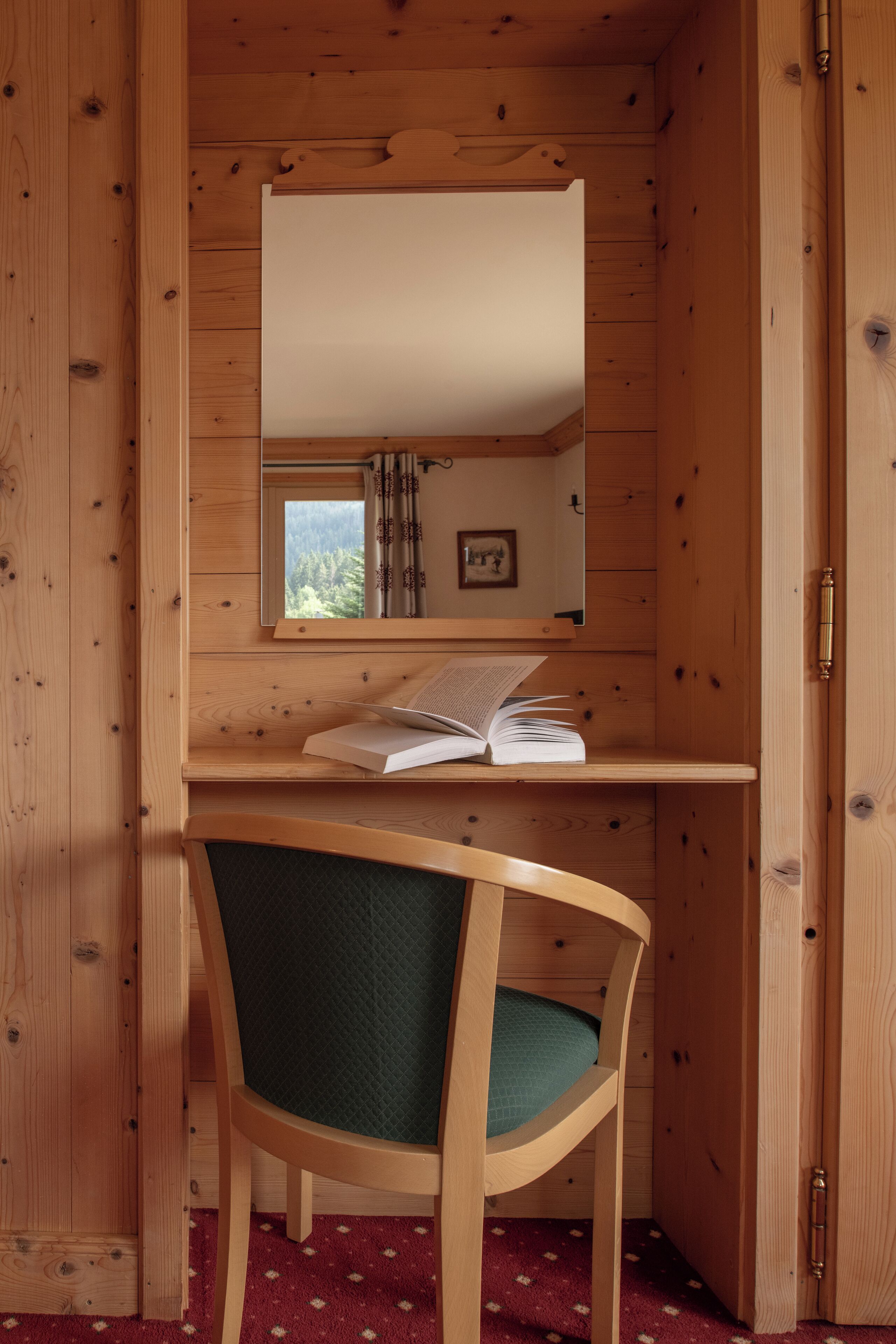 Una habitación de cabaña de madera con escritorio, silla y espejo.
