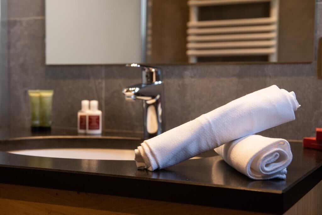 Ein Badezimmer mit einem schwarzen Waschbecken, einem weißen Handtuch und einem Spiegel.