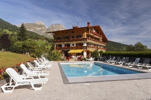 A hotel with a pool, lounge chairs, and a mountainous backdrop. - Le Chamois d'Or (Cordon)