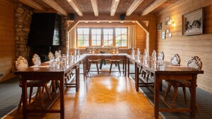 A long wooden dining table with chairs, a stone fireplace, and a large window with multiple panes. - Le Chamois d'Or (Cordon)