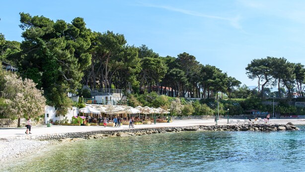 A coastal area with a stone pier, beach umbrellas, and outdoor seating. - Best Location Rooms (Split)