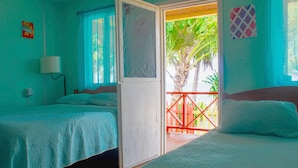 Una habitación con dos camas, un ventanal con vistas a palmeras y una puerta que da a un balcón al aire libre.