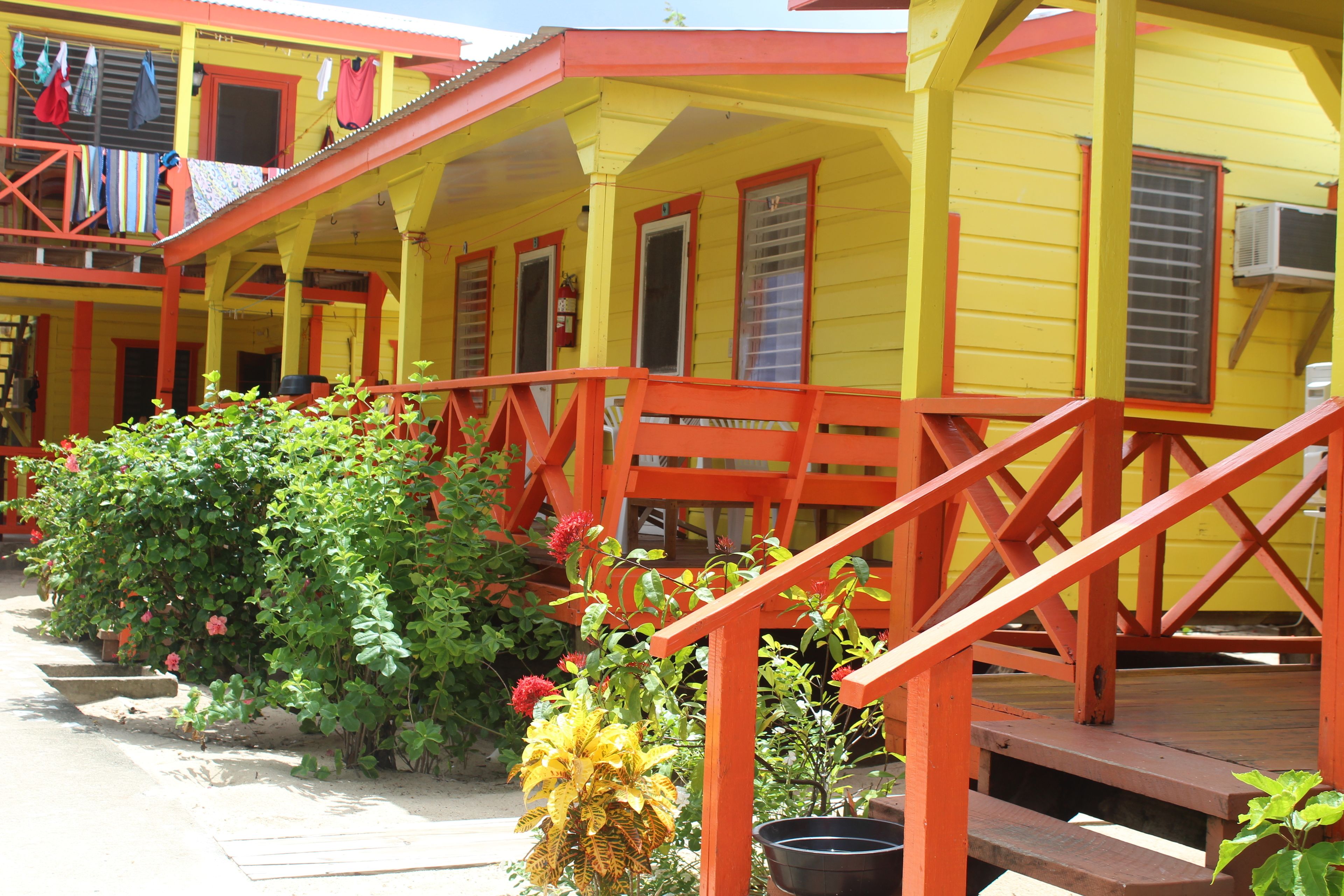 A yellow building with red railings and a porch.