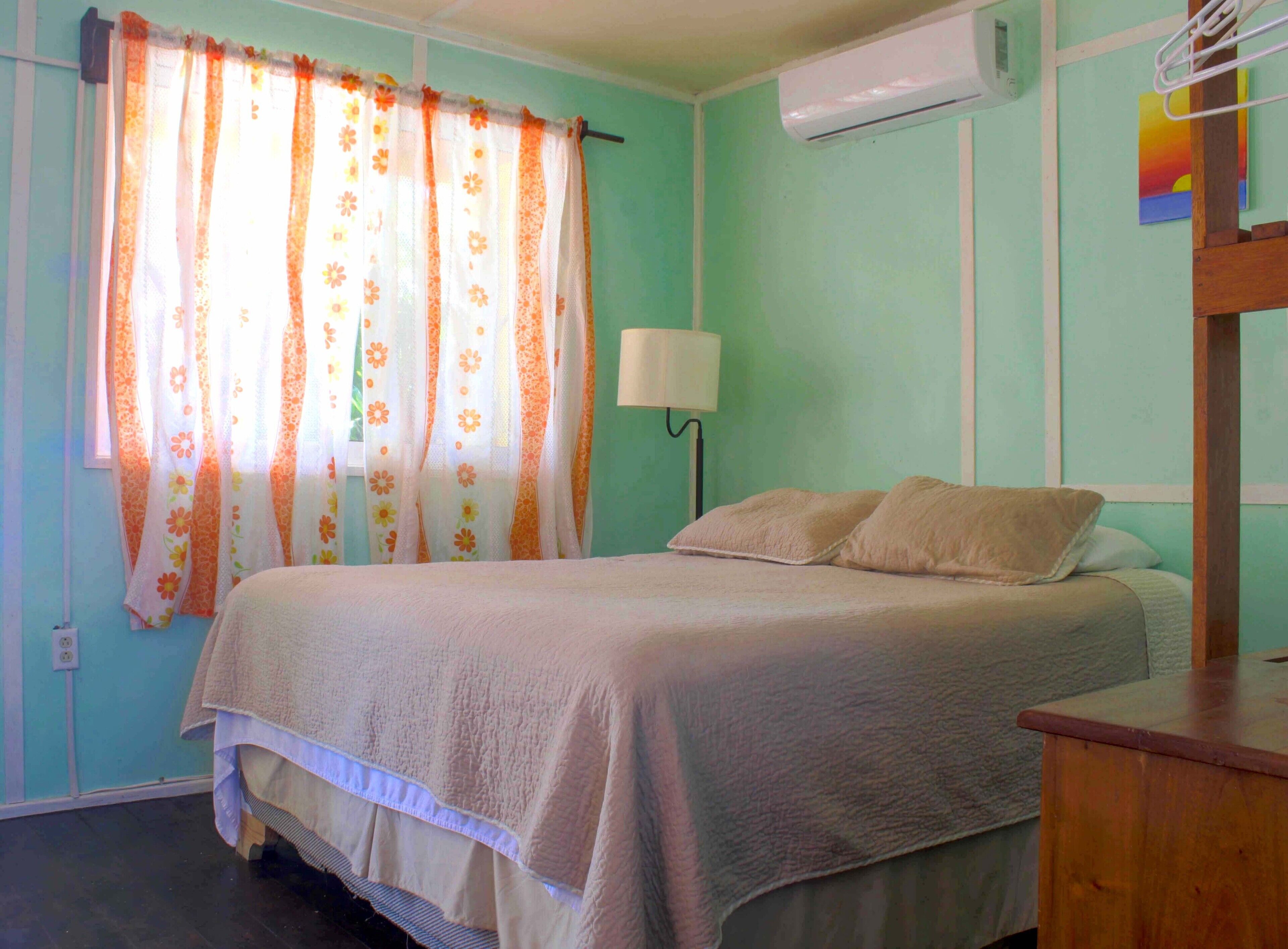 A bedroom with a bed, a nightstand, a lamp, and a window with curtains.