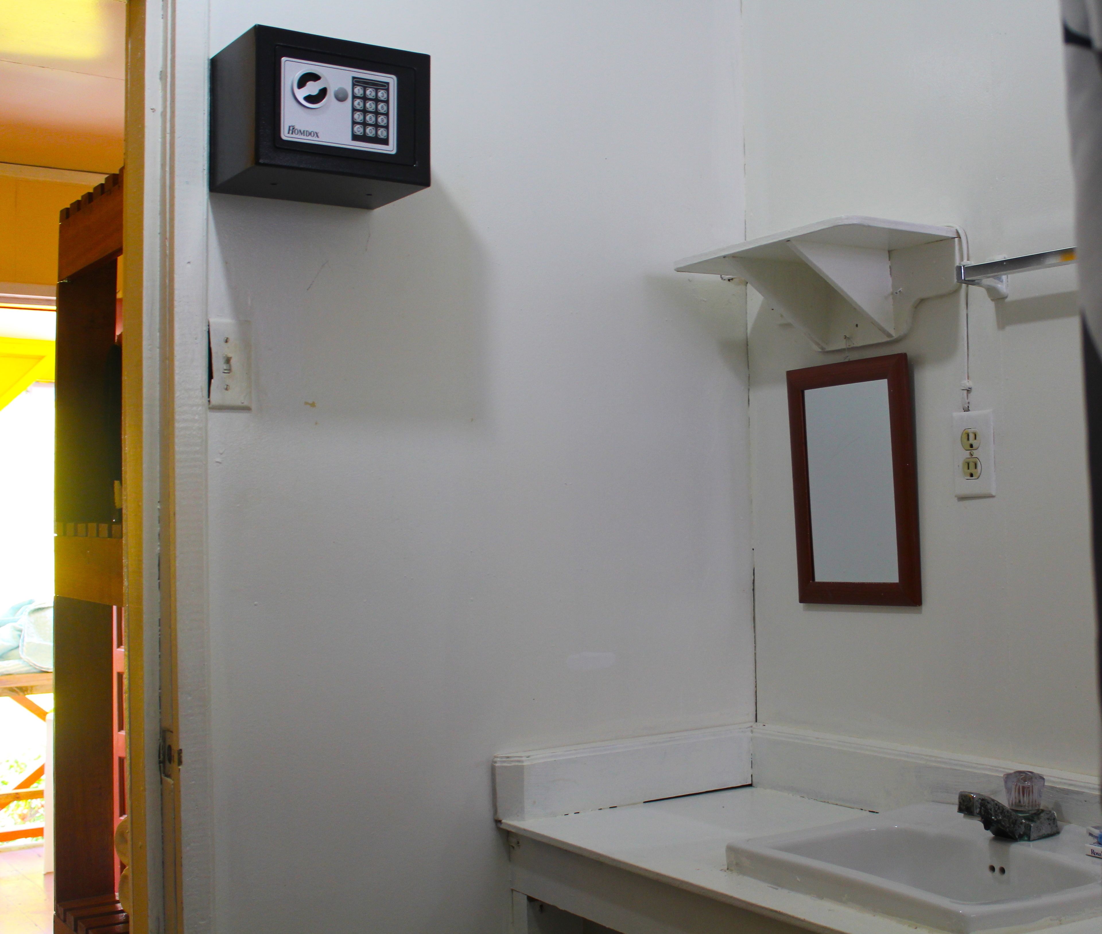 A bathroom with a white sink, a mirror, and a security keypad on the wall.