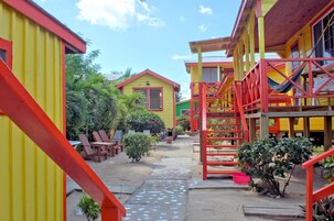 Un patio colorido con edificios amarillos y rojos, asientos al aire libre y una hamaca.