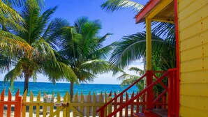 Vista de una playa con un edificio amarillo y una escalera roja que lleva a una terraza de madera.