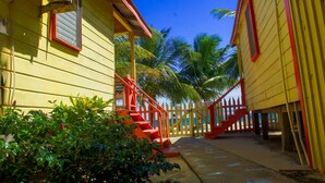Un edificio amarillo con barandillas rojas y una escalera que da a la playa.