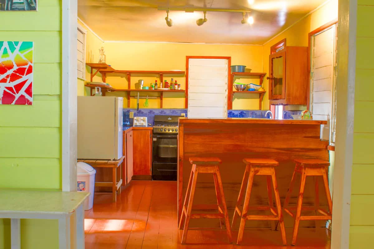 A kitchen with wooden stools, a refrigerator, an oven, and a sink.