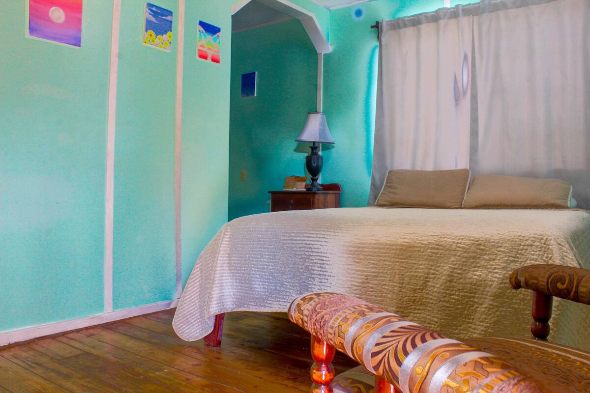 A bedroom with a bed, a nightstand, a lamp, and a chair.