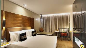 A hotel room with a large bed, bedside tables, a desk, a chair, and a TV.