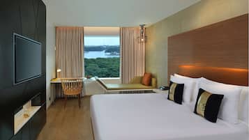 Una habitación de hotel moderna con una cama grande, un televisor, un escritorio con una silla y vistas a un lago.