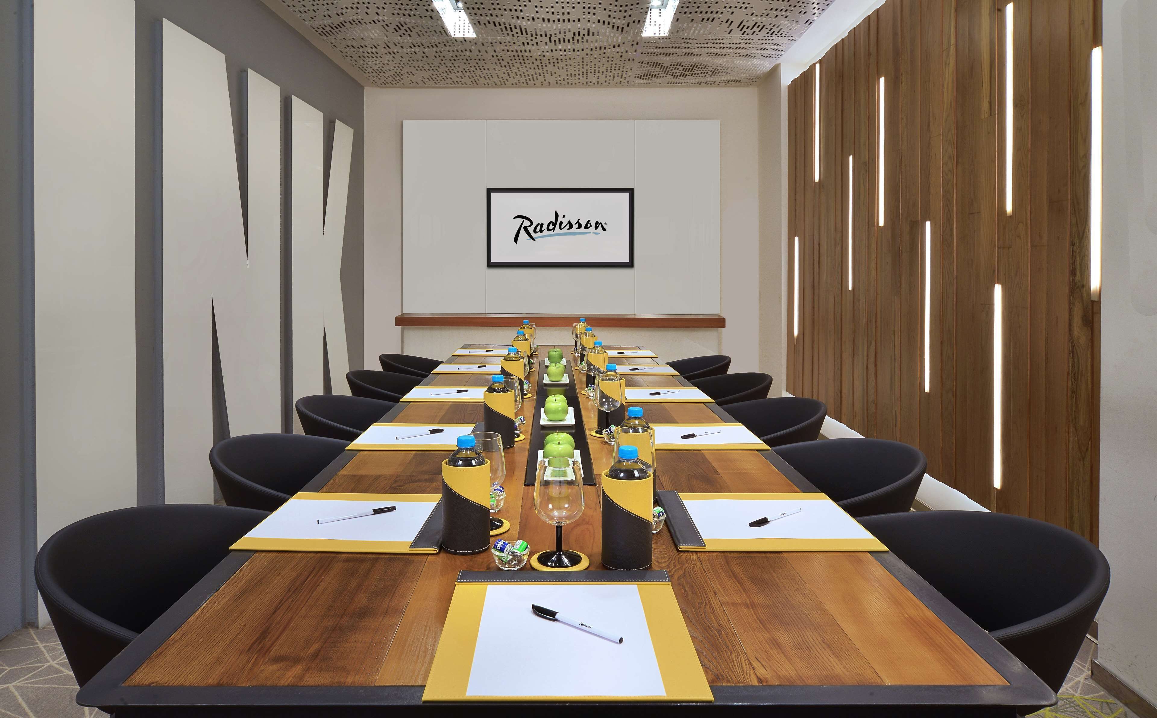 Un salón de conferencias con una larga mesa, sillas negras y el logotipo de Radisson en la pared.