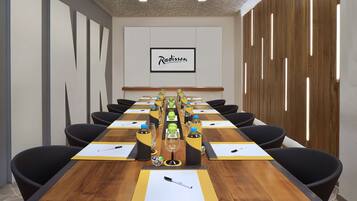 Un salón de conferencias con una larga mesa, sillas negras y el logotipo de Radisson en la pared.