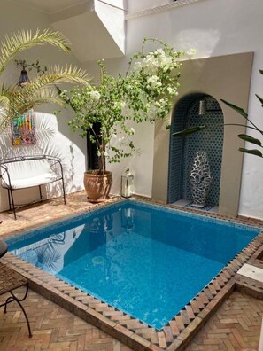 A rectangular swimming pool with a tiled border, surrounded by a brick patio. - Riad Sasha (Marrakech)