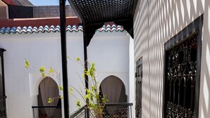 A covered outdoor corridor with a tiled floor, metal railings, and potted plants. - Riad Sasha (Marrakech)