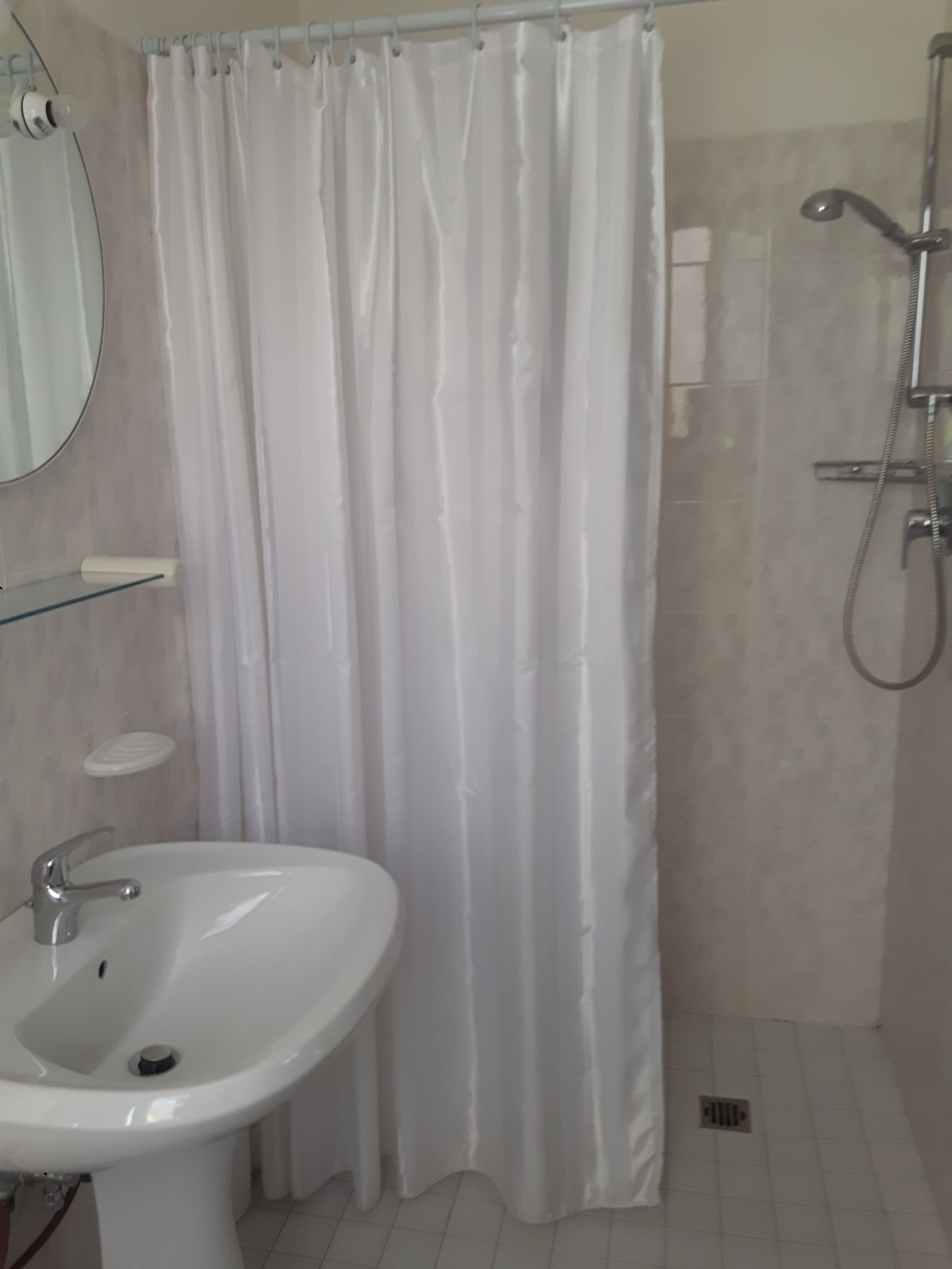 A bathroom with a white sink, a shower, and a curtain.