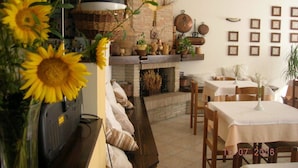 A cozy dining area with a fireplace, wooden furniture, and various plants. - Agriturismo La Selva (Nocera Umbra)