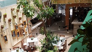 An outdoor dining area with tables and chairs, surrounded by potted plants and string lights. - Suites Calle 8 (Playa del Carmen)