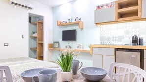 A modern kitchen with a built-in TV, wooden shelves, and a dining area with a table set for two. - Suites Calle 8 (Playa del Carmen)
