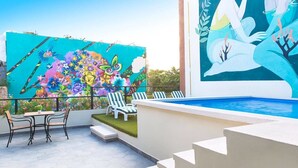 A rooftop terrace with a pool, lounge chairs, and a colorful mural. - Suites Calle 8 (Playa del Carmen)